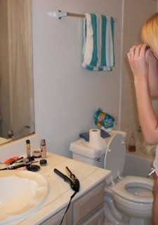 18 years old teen in glasses strips in bathroom